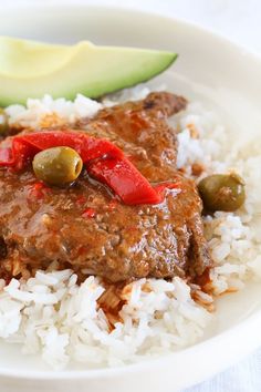 a close up of a plate of food with rice and an avocado on the side