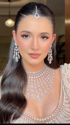 a woman with long dark hair wearing an elaborate necklace and earring on her head