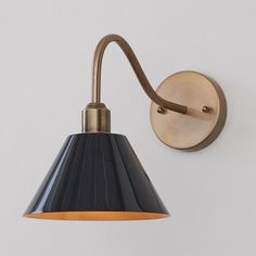 a wall light with a black shade on the side and a brown cord attached to it