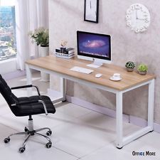 a desk with a computer on it in front of a window and pictures hanging on the wall