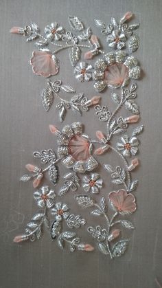 some pink flowers and leaves on a gray surface with silver trimmings, along with other decorative items