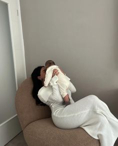 a woman sitting on top of a chair holding a baby