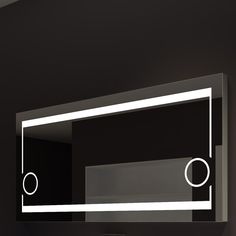 a bathroom mirror that is reflecting the light on it's side wall mounted in a dark room