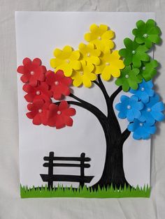 a paper tree with flowers and a bench in the grass on a white sheet of paper