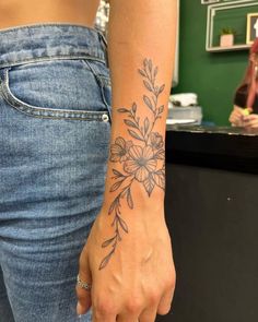 a woman with a flower tattoo on her left arm and wrist is standing in front of a counter