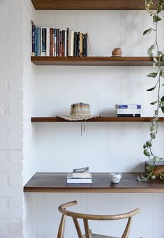 a wooden table with two books on it and a plant in the corner next to it