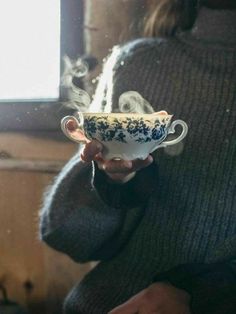 a woman holding a cup with steam coming out of it