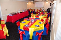 a banquet room set up with red, yellow and blue tables