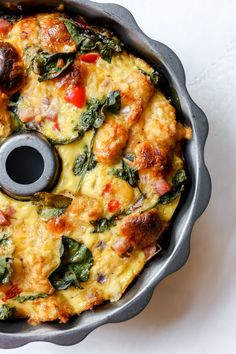 an omelet with spinach and cheese in a metal pan on a white surface