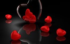 some red hearts on a black surface with reflections in the water and one heart shaped