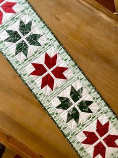 the table runner is decorated with red, green and white quilted poinsettis