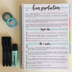 an open notebook with writing on it next to some pens and markers, including two markers