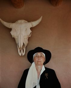 an old man wearing a black hat next to a cow skull and quote from george o'keefeef