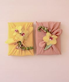 two yellow and pink flowered napkins with bows on them are sitting next to each other