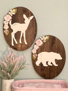 two wooden deer and bear cutouts on the wall above a crib with pink flowers