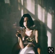 a woman sitting in a chair holding a bowl