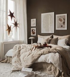 a bed sitting in a bedroom next to a window with pictures on the wall above it