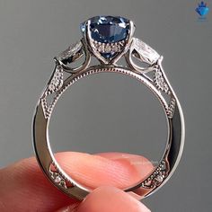 someone is holding an engagement ring with a blue stone in the center and diamonds around it