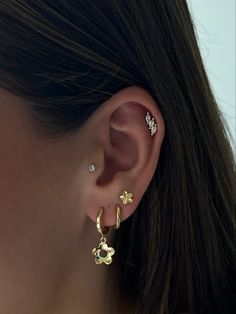 a close up of a woman's ear wearing gold earrings with flowers on them