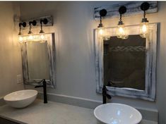 a bathroom with two sinks, mirrors and lights on the wall above them is pictured in this image