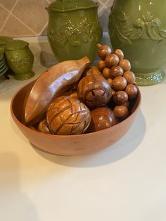 a bowl filled with nuts sitting on top of a counter next to two green vases