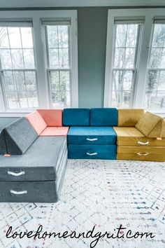 a living room filled with furniture next to two windows and a rug on the floor