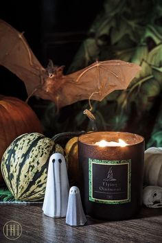 a candle that is sitting on a table next to other halloween decorations and pumpkins