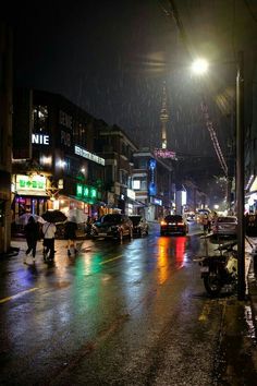 people with umbrellas are walking in the rain on a city street at night time