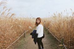 a woman is walking down a path through tall grass