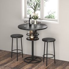 a small table with three stools in front of a window