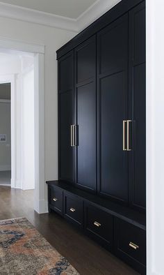 a large black cabinet with gold handles in a white walled room next to a doorway