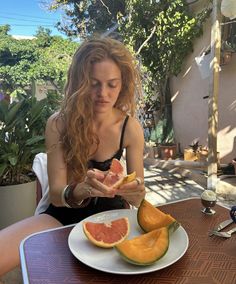 a woman sitting at a table with some fruit on it