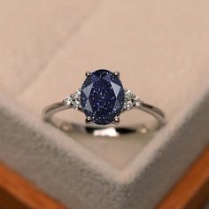 a blue diamond ring sitting on top of a box