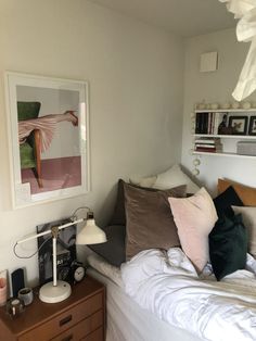 a bed room with a neatly made bed and a painting on the wall above it