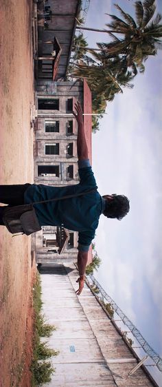 a man is jumping in the air with his skateboard near a building and palm trees