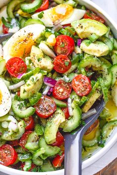 a bowl filled with cucumber, tomatoes and hard boiled eggs