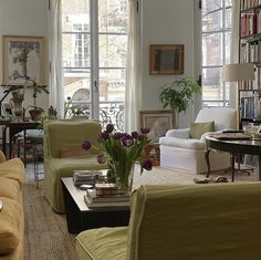 a living room filled with lots of furniture and bookshelves next to a window