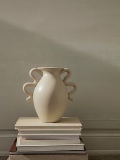 a white vase sitting on top of some books