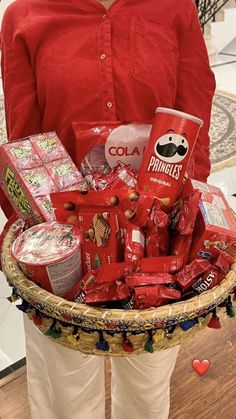 a woman is holding a basket full of snacks and condiments for valentine's day