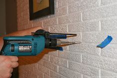 a person using a drill to fix a brick wall