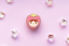 a pin sitting on top of a pink surface surrounded by small crystal beads and other items