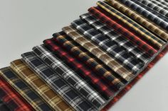 many different colored flannel fabrics are lined up in rows on a white surface