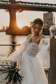 a woman in a white dress is standing near the water