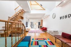 an open floor plan with stairs, couches and rugs on the wooden floor