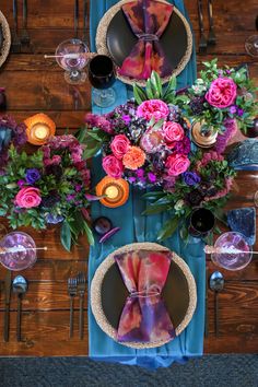 the table is set with colorful flowers and place settings