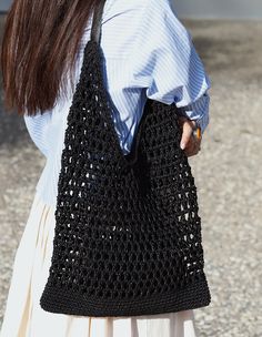 a woman carrying a black crocheted purse