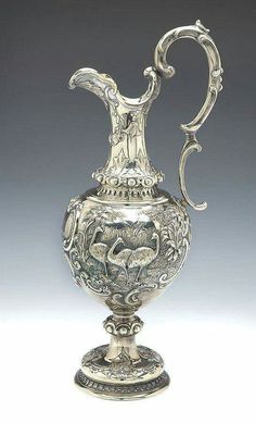 an ornate silver vase is on display against a gray background