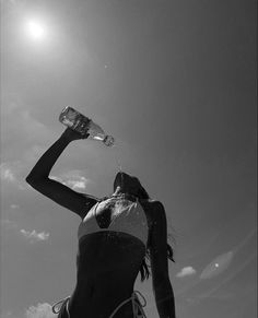 a woman in a bathing suit drinking water from a bottle