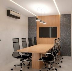 an empty conference room with black chairs and a wooden table in front of a flat screen tv mounted on the wall