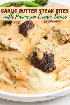 garlic butter steak bites with parmesan cream sauce in a white bowl next to asparagus